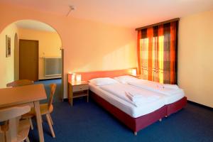 a hotel room with a bed and a desk and a table at Euro Youth Hotel & Krone in Bad Gastein