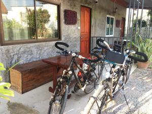 duas bicicletas estacionadas em frente a uma casa com um banco em Muangchaem House em Mae Chaem