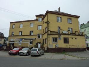 żółty budynek z samochodami zaparkowanymi przed nim w obiekcie Hotel Paradise w Ostravie