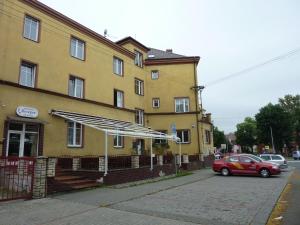 a red car parked in front of a yellow building at Hotel Paradise in Ostrava