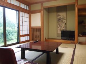 a living room with a table and a tv at Oshi Ryokan in Nagano
