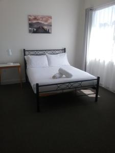 Tullah的住宿－塔拉小酒館酒店，一间卧室配有一张带白色床单的床和一扇窗户。