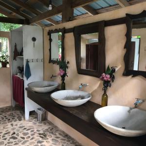 a bathroom with three sinks and two mirrors at Sattva Land in Belmopan