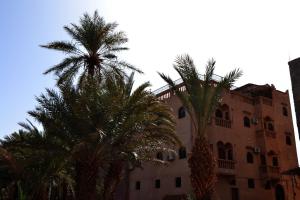 a building with palm trees in front of it at Dar nadia bendriss in Ouarzazate