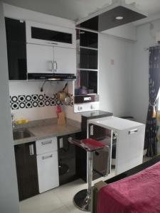 eine kleine Küche mit weißen Schränken und einem Barhocker in der Unterkunft Apartment Green Pramuka ~ OCR in Jakarta