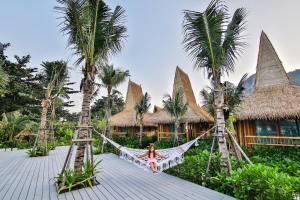 a woman sitting on a hammock in front of a resort at Phi Phi CoCo Beach Resort in Phi Phi Islands