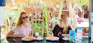 two women sitting at a table with plates of food at Deep House Bungalows in Gili Trawangan