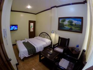 um pequeno quarto com uma cama, uma mesa e uma secretária em The Executive Villa Inn & Suites em Dávao