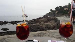 dos vasos con fruta en ellos sentados en una mesa junto al océano en location Coma Chéric et parking, en Collioure