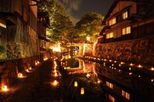 un gruppo di candele sul lato di un edificio di notte di 近江の町家 門 a Omihachiman