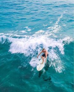 un homme chevauchant une vague sur une planche de surf dans l'océan dans l'établissement Rovenluck Eco Cabana, à Weligama