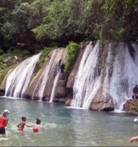 a group of children playing in the water in front of a waterfall at Becaville in Port Antonio