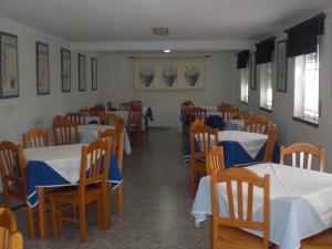 a restaurant with tables and chairs with blue and white tablecloths at Hotel Branco II in Praia da Vitória