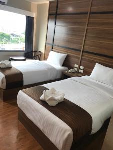a hotel room with two beds and a window at ATK Garden Hills in Hat Yai