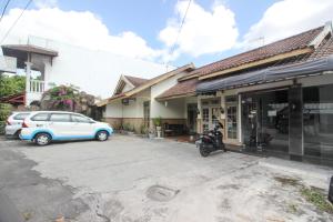 ein Auto parkt auf einem Parkplatz neben einem Haus in der Unterkunft RedDoorz near RS Sarjito Yogyakarta 2 in Yogyakarta