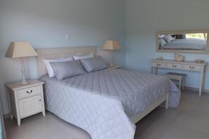 a bedroom with a white bed with two nightstands and a mirror at Myoli Holiday Apartments in Sedgefield
