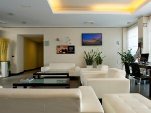 - un salon doté d'un mobilier blanc et d'une table dans l'établissement Mercure Bergamo Aeroporto, à Stezzano