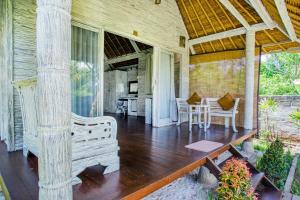 a porch of a house with a bench and a table at Bay Shore Huts - CHSE Certified in Nusa Lembongan