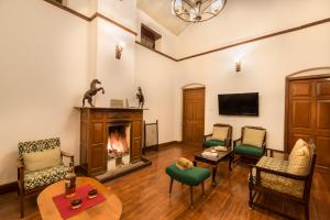 a living room with a fireplace and a tv at SaffronStays Milton Abbott Estate, Ooty in Ooty