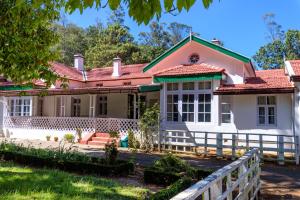 ein Haus mit rotem Dach und einem Zaun in der Unterkunft SaffronStays Milton Abbott Estate, Ooty in Udagamandalam