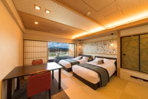 a hotel room with two beds and a table and a television at Juhachiro in Gifu