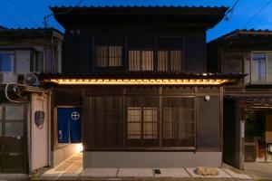 una casa con un cancello e luci sopra di Ainotsuji Machiya House a Kanazawa