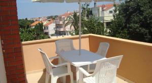 una mesa blanca y sillas en un balcón con sombrilla en Apartments and Rooms Antonio en Zadar