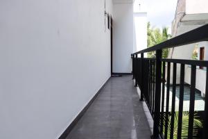 a balcony with a black railing and a white wall at Sakura Calm Rest in Mirissa