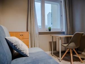 1 dormitorio con sofá azul, escritorio y ventana en Apartament Olsztyńska en Gdansk