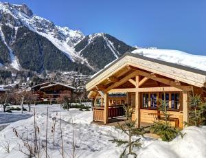 una cabaña en la nieve con montañas en el fondo en Chalets Ile des Barrats, en Chamonix-Mont-Blanc