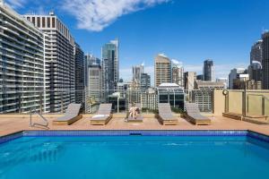 een persoon op het dak van een gebouw met een zwembad bij Park View Apartment in Sydney