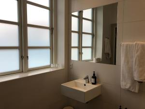 a white bathroom with a sink and two windows at Hotel Løkken Strand in Løkken