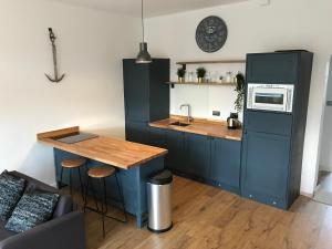 cocina con armarios azules y mesa con microondas en 1 bed river apartment on the docks en Gloucester
