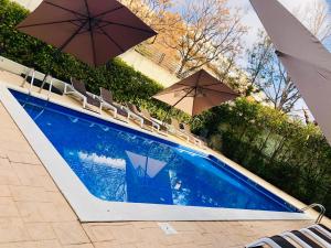 una piscina con due ombrelloni e sedie di Salou Med Apartamentos a Salou