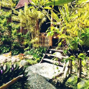 un jardín con una pasarela de madera y algunas plantas en Melati Bali Homestay, en Canggu