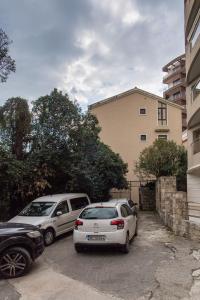 two cars parked in a parking lot in front of a building at Guest House Mandarina in Budva