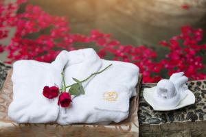 due asciugamani e due rose su un tavolo con fiori rossi di Yun'an Huidu Hotel a Kunming
