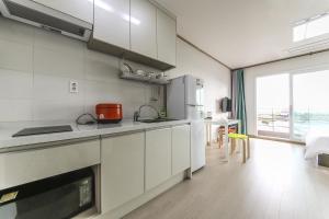 a kitchen with white cabinets and a large window at Jeju Soo Pension in Seogwipo