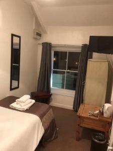 Schlafzimmer mit einem Bett mit einem Spiegel und einem Fenster in der Unterkunft Markets Tavern Hotel in Brecon