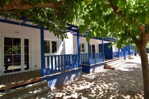 una fila de casas azules y blancas con un árbol en Camping La Rueda, en Cubelles