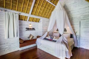 a bedroom with a bed with a mosquito net at Bay Shore Huts in Nusa Lembongan