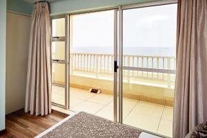 een slaapkamer met glazen schuifdeuren en uitzicht op de oceaan bij First Group The Palace All-Suite in Durban