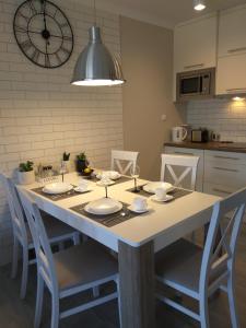 a kitchen with a table with chairs and a clock on the wall at Apartament Luxury in Pogorzelica