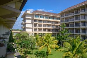 um edifício de apartamentos com palmeiras em frente em Lombok Raya Hotel em Mataram