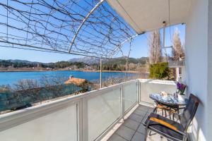 een balkon met een tafel en stoelen en uitzicht op een meer bij Apartments Barbir in Ploče