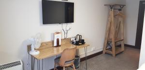 a wooden desk with a television on a wall at Waterloo Cross, Devon by Marston's Inns in Uffculme