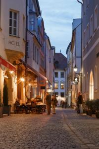 Un groupe de personnes marchant dans une rue la nuit dans l'établissement Hotel Orphée - Großes Haus, à Ratisbonne