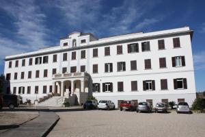 罗马Ostello Villa Monte Mario的一座白色的大建筑,前面有汽车停放