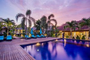 una piscina con sillas azules y palmeras en Bay Shore Huts, en Nusa Lembongan