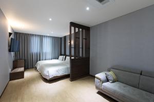 Habitación de hotel con cama y sofá en Notte La Mia Hotel, en Busan